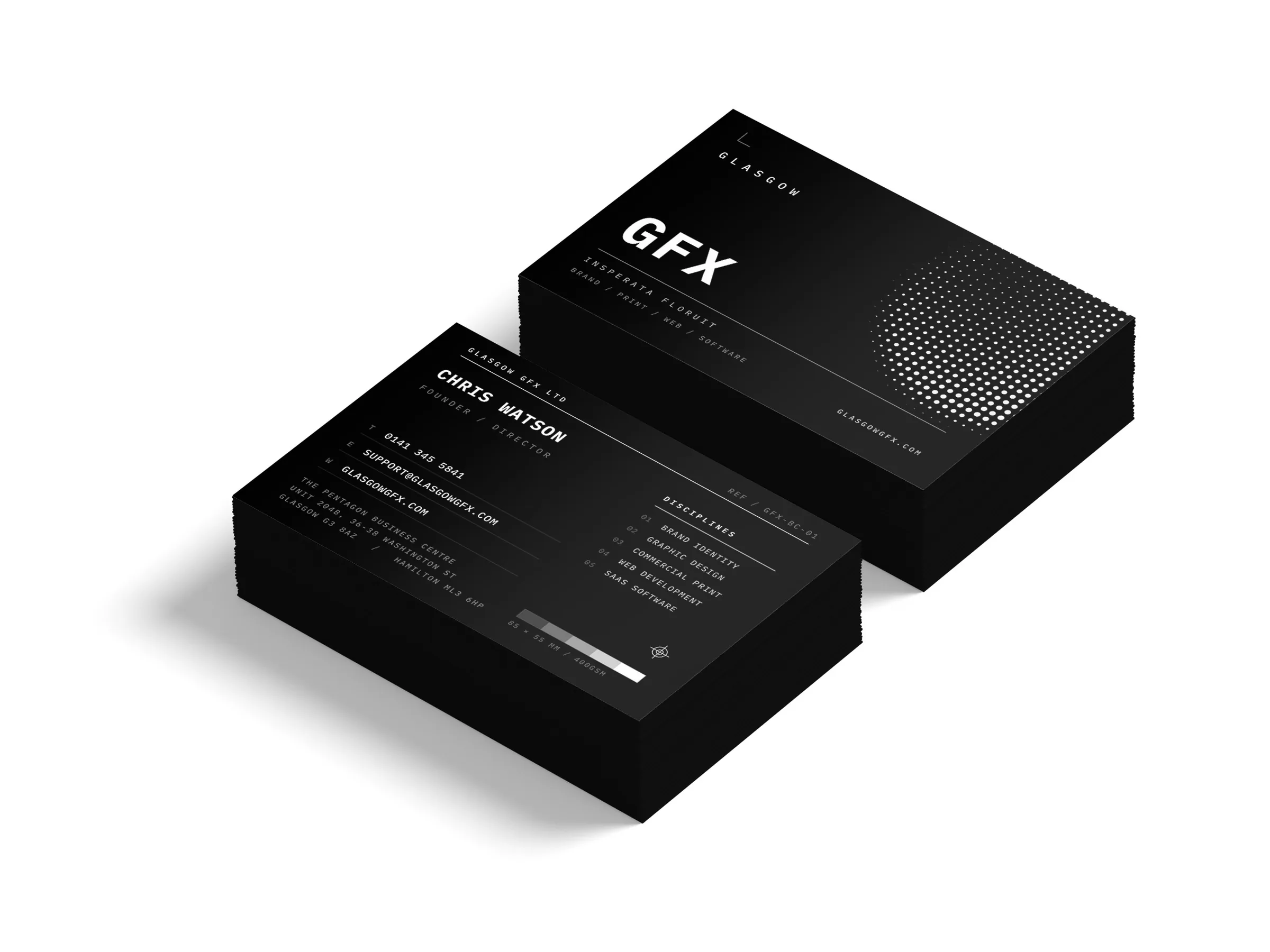 Double-sided 85x55mm business cards printed on black stock, front and back, in two stacks on a white studio surface