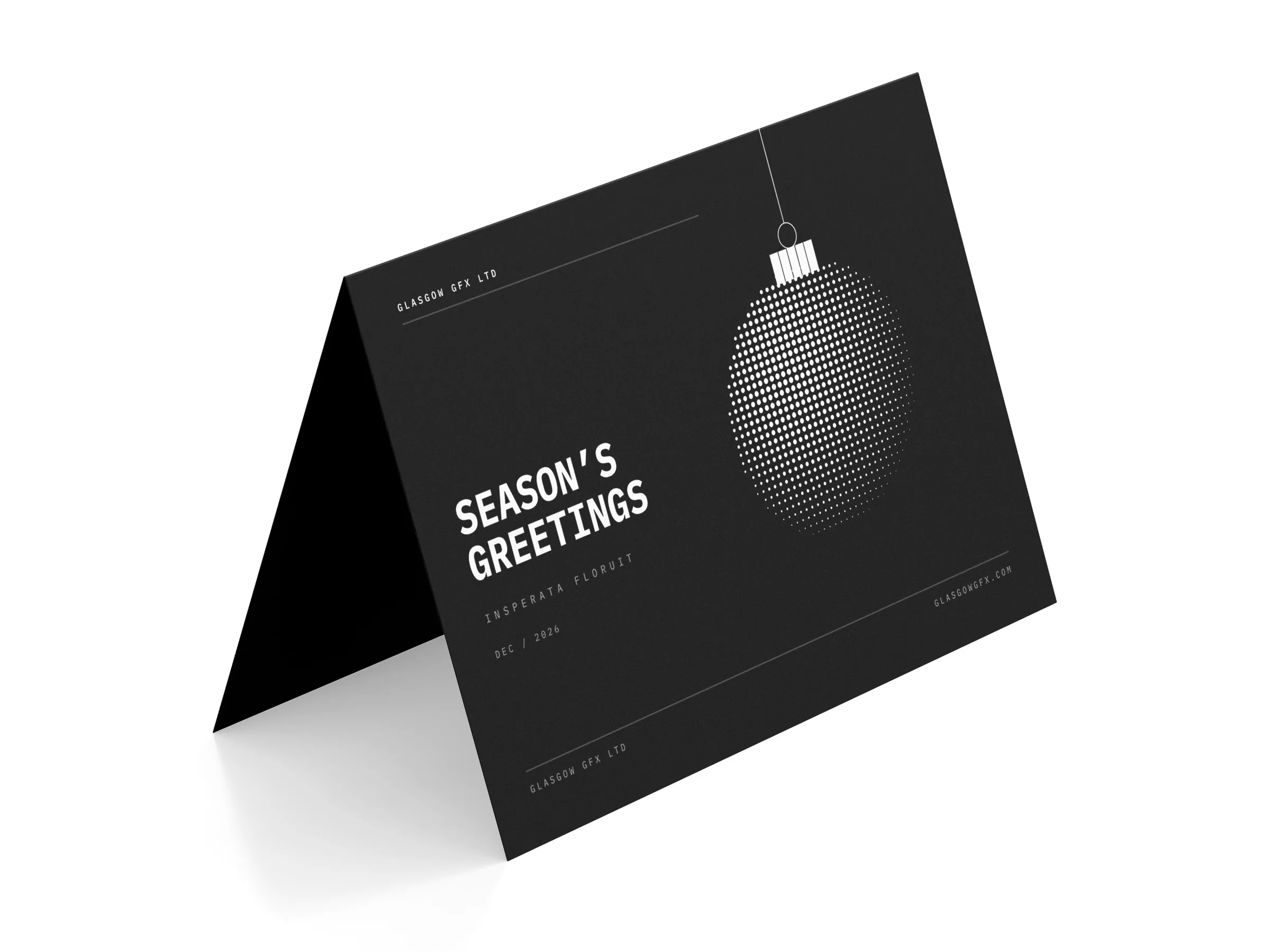 Folded A6 Christmas card with a halftone bauble, standing on a white studio surface