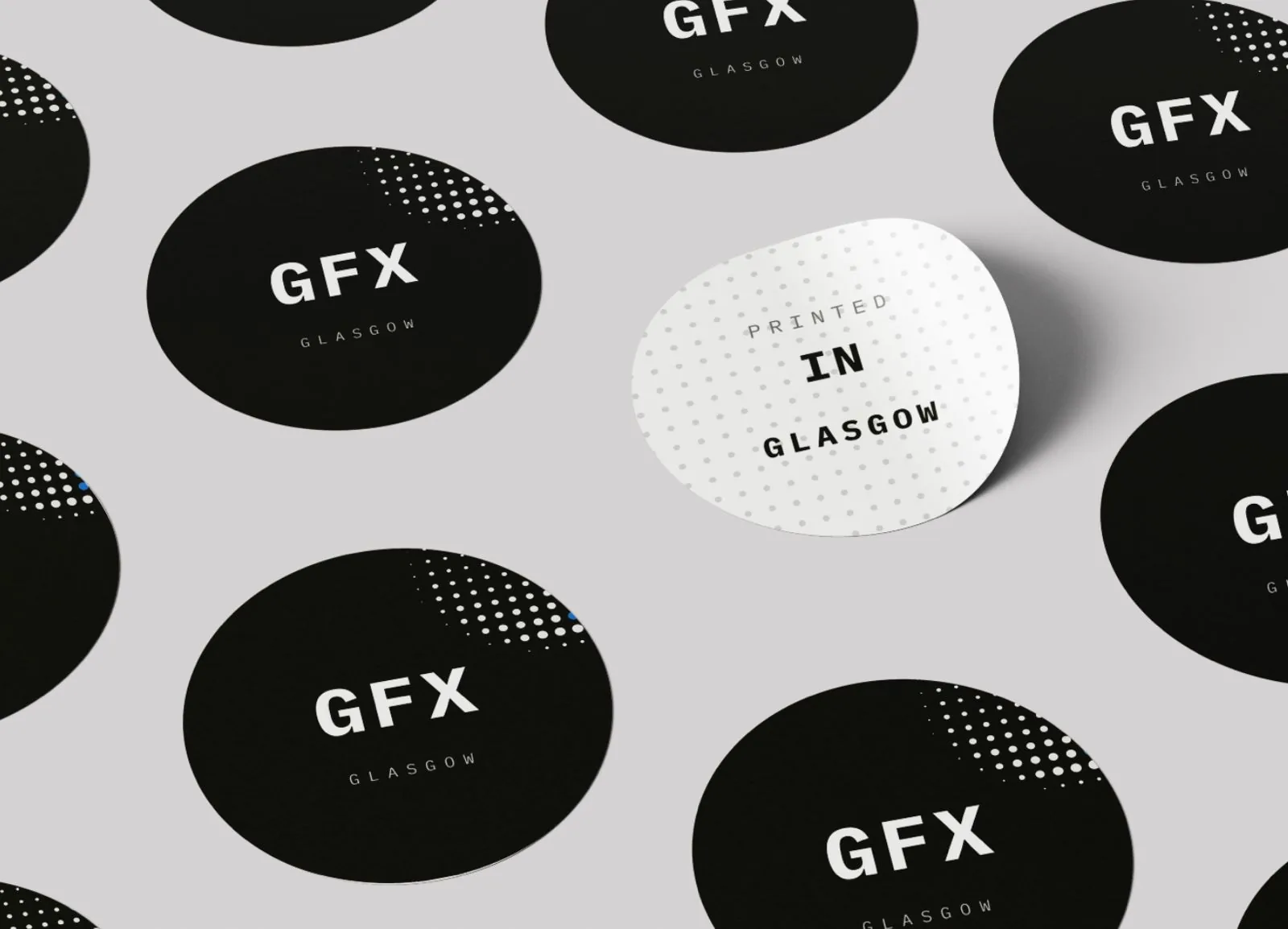A grid of circular Glasgow GFX stickers, black with a white GFX logotype, with one white sticker in the middle reading Printed in Glasgow.
